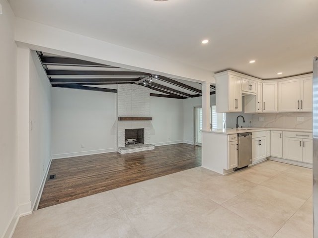 kitchen featuring lofted ceiling with beams, a sink, tasteful backsplash, light countertops, and dishwasher