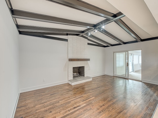 unfurnished living room featuring lofted ceiling with beams, baseboards, a brick fireplace, and wood finished floors