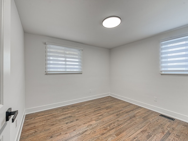 unfurnished room with wood finished floors, visible vents, and baseboards