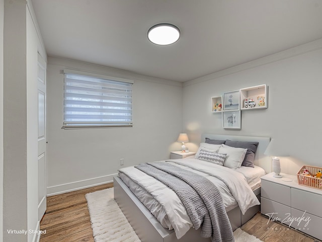 bedroom with crown molding, wood finished floors, and baseboards