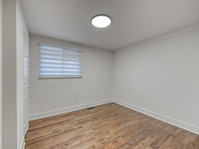 spare room featuring visible vents, ornamental molding, baseboards, and wood finished floors