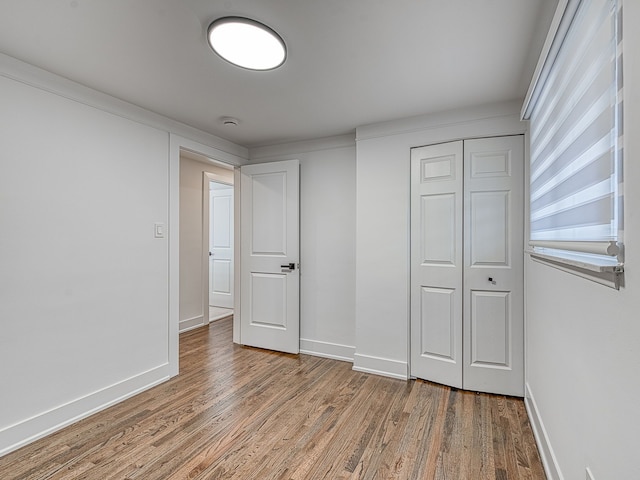 unfurnished bedroom with a closet, baseboards, and wood finished floors