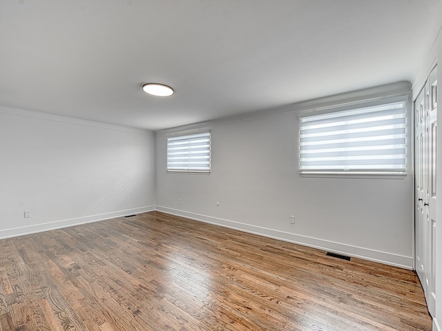 unfurnished room with visible vents, baseboards, and wood finished floors