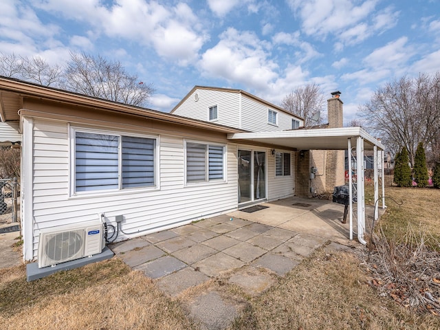 rear view of property with a carport, a chimney, a patio, and ac unit