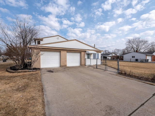 view of front facade with a gate, brick siding, driveway, and fence