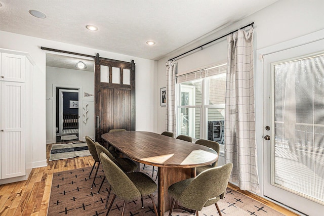 dining room featuring recessed lighting, a barn door, baseboards, and light wood-style floors