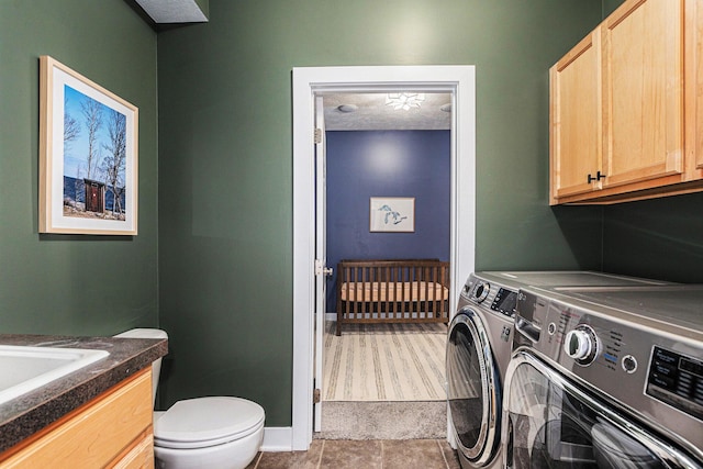 clothes washing area with a sink, baseboards, independent washer and dryer, and a textured ceiling