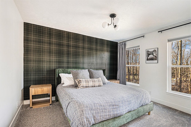 bedroom featuring wallpapered walls, an accent wall, baseboards, and carpet