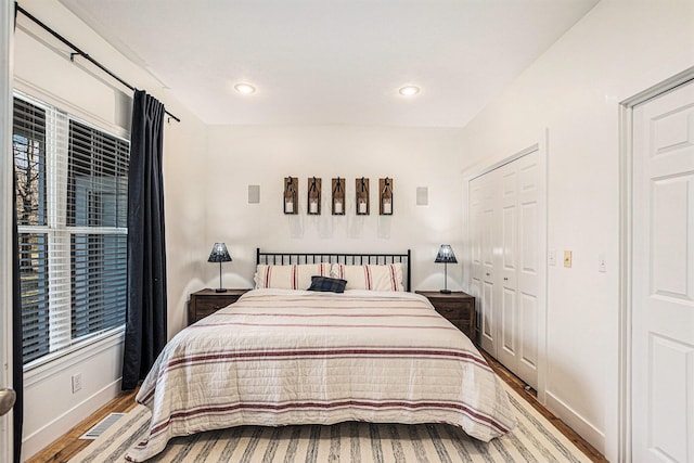 bedroom with wood finished floors, visible vents, baseboards, recessed lighting, and a closet