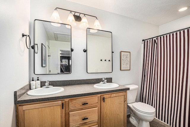 bathroom featuring a textured ceiling, double vanity, toilet, and a sink