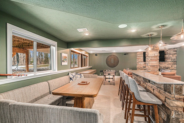 carpeted dining room featuring a textured ceiling, visible vents, indoor bar, and breakfast area