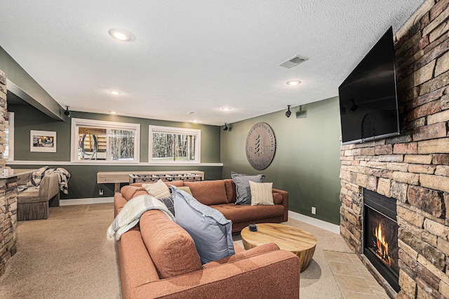 living room featuring a stone fireplace, baseboards, visible vents, and a textured ceiling