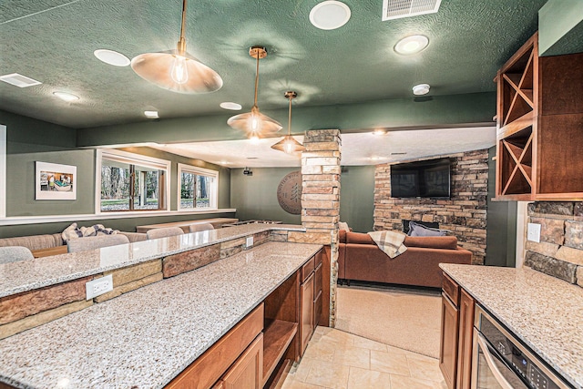 kitchen featuring visible vents, light stone countertops, a textured ceiling, and open floor plan