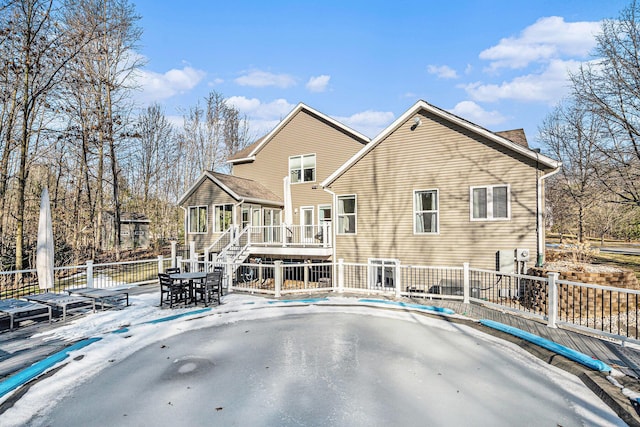 rear view of property featuring outdoor dining area, fence, stairs, and a sunroom