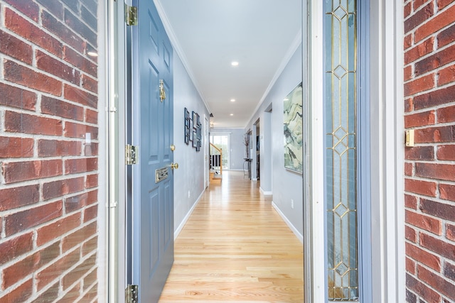 hallway with baseboards, brick wall, light wood-style flooring, recessed lighting, and crown molding