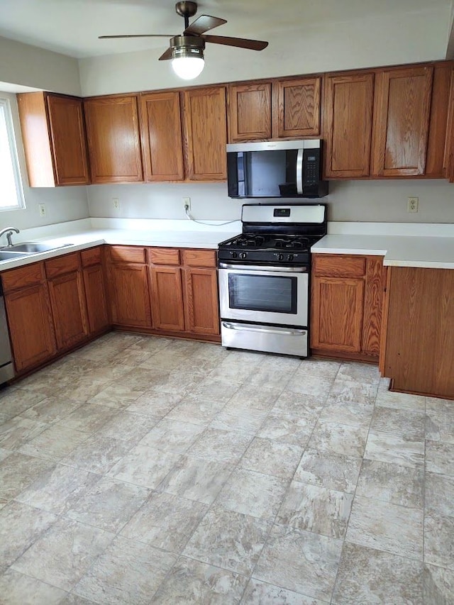 kitchen featuring a sink, appliances with stainless steel finishes, brown cabinetry, and light countertops