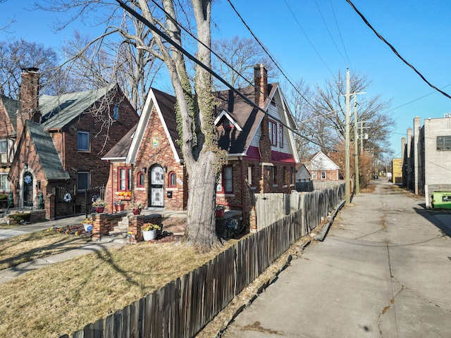 view of front of property featuring brick siding, a chimney, and a fenced front yard