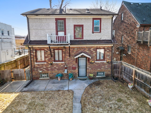 back of property featuring a patio area, a balcony, brick siding, and fence