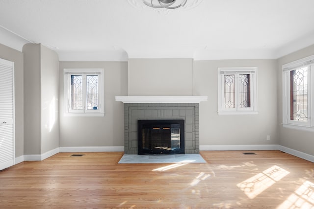 unfurnished living room featuring visible vents, baseboards, wood finished floors, and a tile fireplace