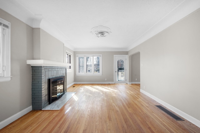 unfurnished living room featuring visible vents, light wood-style flooring, a fireplace, and baseboards