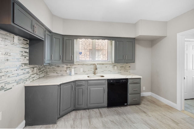 kitchen featuring gray cabinetry, a sink, tasteful backsplash, black dishwasher, and baseboards