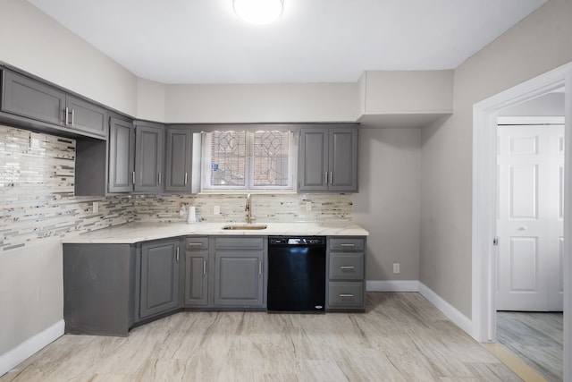 kitchen with decorative backsplash, gray cabinetry, black dishwasher, and a sink