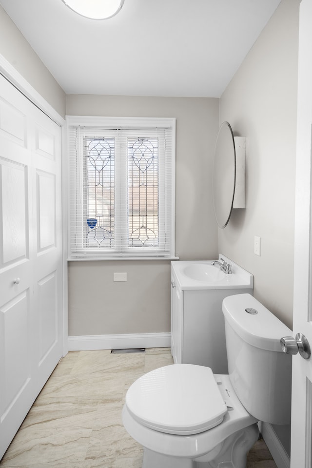 half bath with vanity, toilet, and baseboards