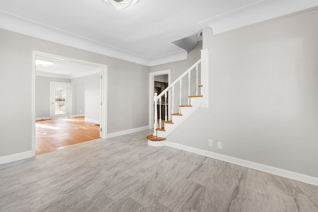 empty room with crown molding, stairs, baseboards, and wood finished floors