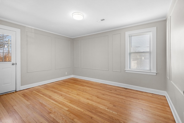 empty room with a decorative wall, plenty of natural light, visible vents, and light wood-type flooring