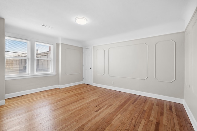 empty room featuring visible vents, light wood-style flooring, and baseboards