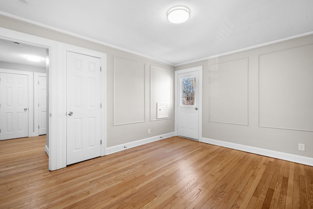 unfurnished bedroom featuring a decorative wall, light wood-style floors, and baseboards