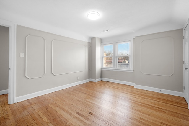 empty room with visible vents, baseboards, and hardwood / wood-style flooring