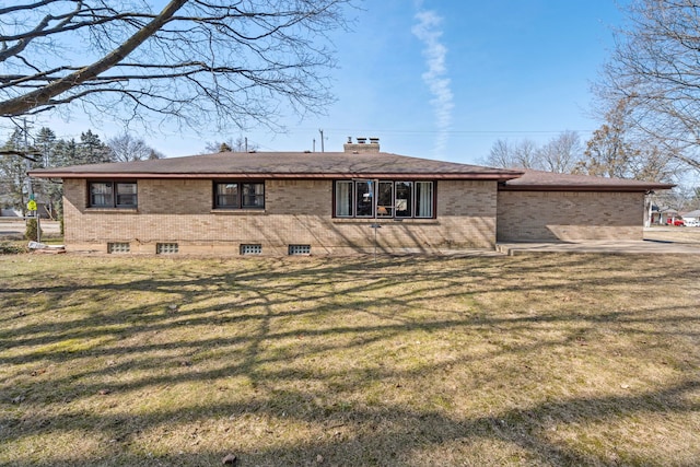 rear view of property featuring a lawn, brick siding, and a chimney