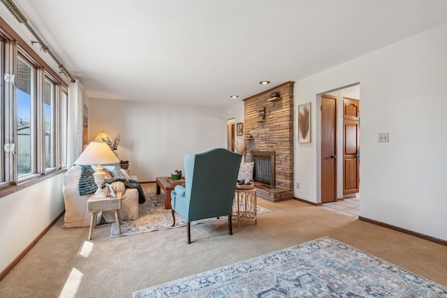 living area featuring a stone fireplace, light colored carpet, and baseboards