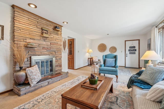 living room featuring recessed lighting, a stone fireplace, light colored carpet, and baseboards