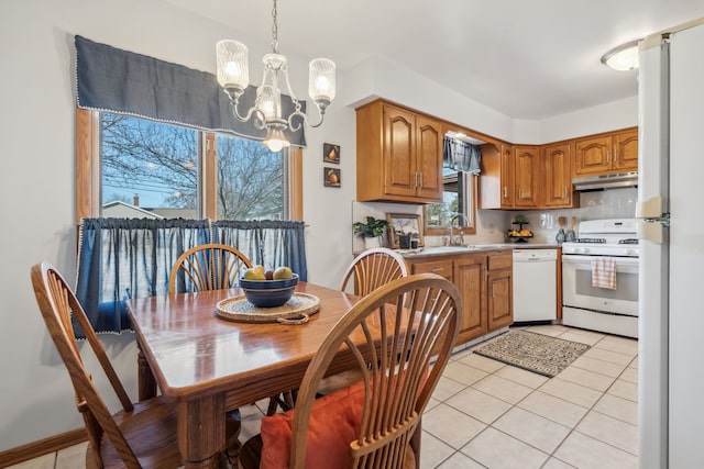 kitchen featuring under cabinet range hood, light tile patterned floors, brown cabinetry, white appliances, and a sink