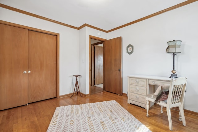 bedroom with a closet, ornamental molding, baseboards, and wood finished floors