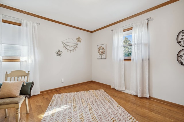 sitting room with crown molding, baseboards, and light wood-type flooring