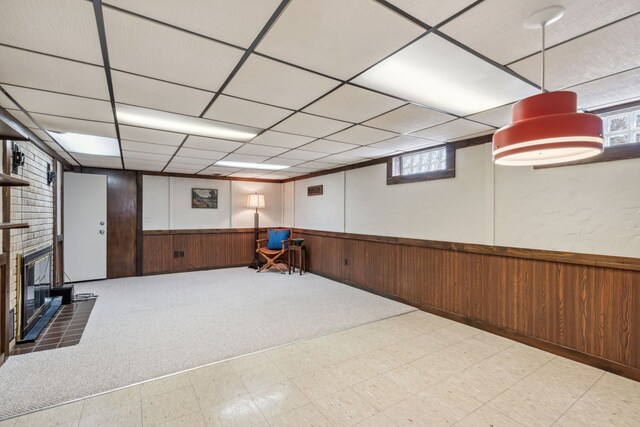 below grade area with tile patterned floors, a brick fireplace, wood walls, and wainscoting