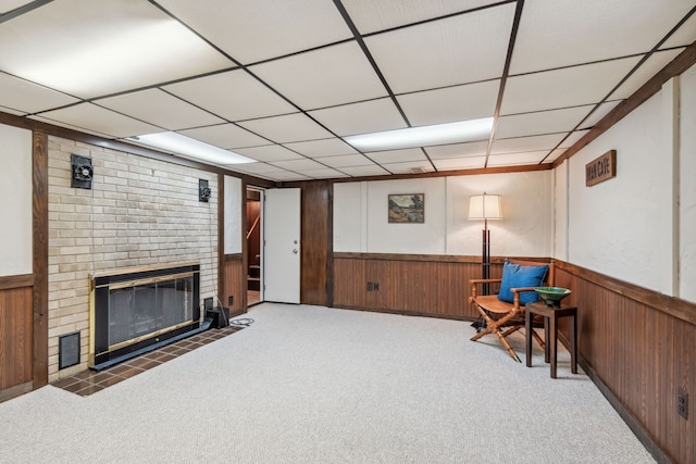 sitting room with a brick fireplace, wooden walls, and wainscoting