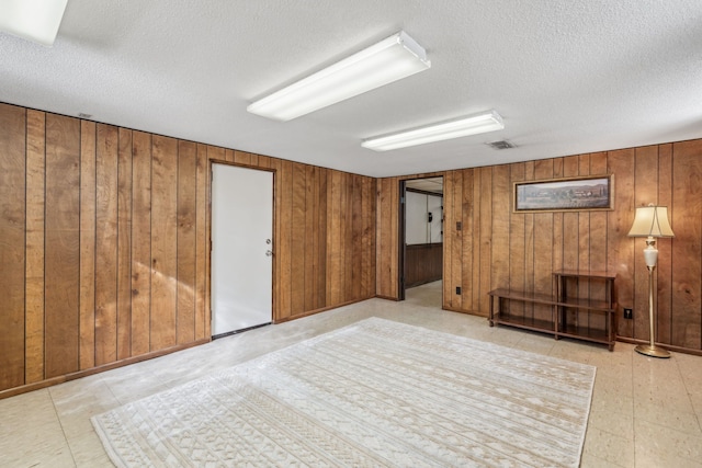 interior space with visible vents, wood walls, and a textured ceiling