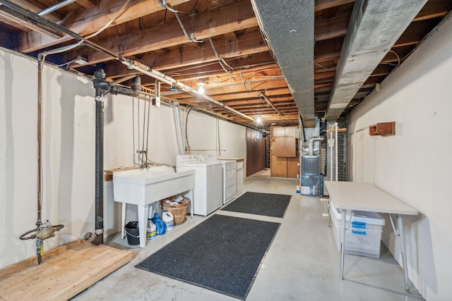 unfinished basement featuring a sink, heating unit, and independent washer and dryer