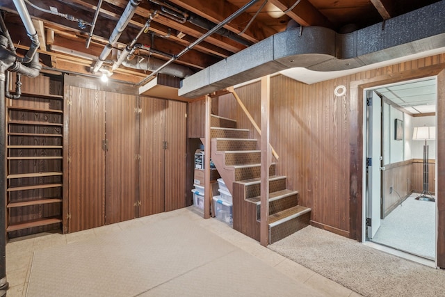 unfinished basement featuring stairway and wooden walls