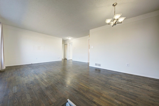 unfurnished room featuring visible vents, baseboards, a notable chandelier, a textured ceiling, and dark wood-style flooring