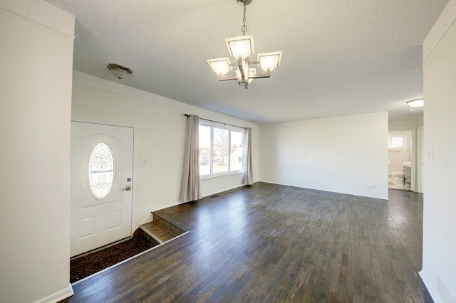 entrance foyer with dark wood finished floors, a textured ceiling, and an inviting chandelier