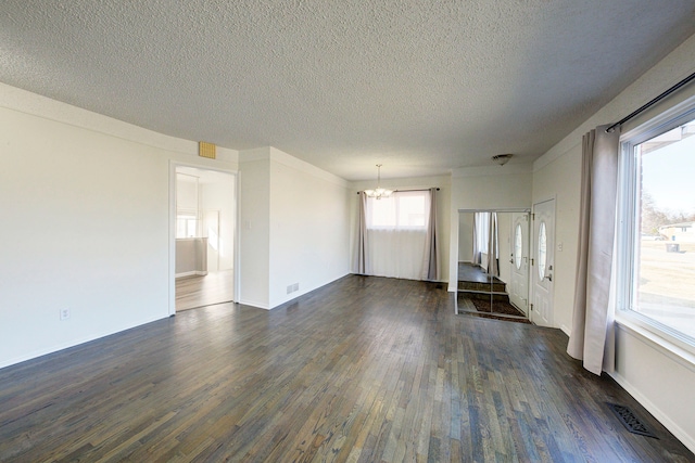 unfurnished living room with visible vents, baseboards, dark wood finished floors, an inviting chandelier, and a textured ceiling