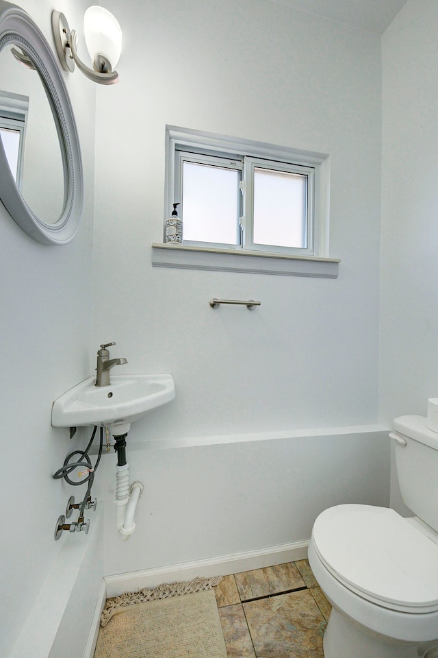 half bathroom featuring tile patterned floors, baseboards, and toilet