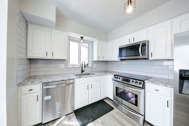 kitchen with backsplash, light stone countertops, appliances with stainless steel finishes, and a sink