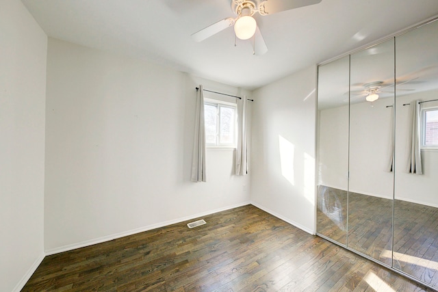 unfurnished bedroom with hardwood / wood-style flooring, multiple windows, baseboards, and a closet