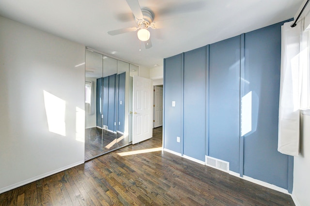 unfurnished bedroom with ceiling fan, wood finished floors, visible vents, and baseboards